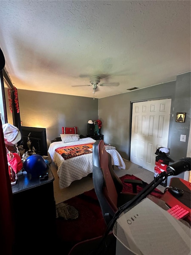 carpeted bedroom featuring a textured ceiling and ceiling fan