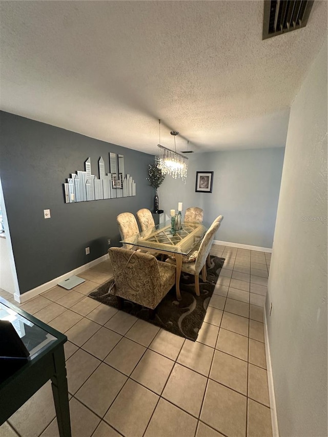 tiled dining room with a textured ceiling and a chandelier