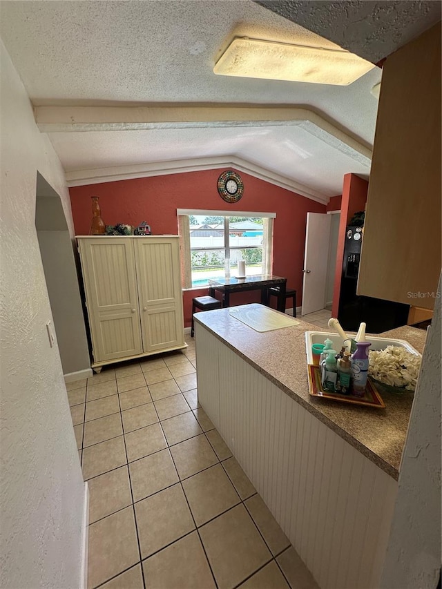 kitchen with a textured ceiling, light tile patterned flooring, and lofted ceiling