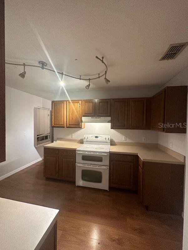 kitchen with a textured ceiling, dark hardwood / wood-style flooring, and white range with electric stovetop