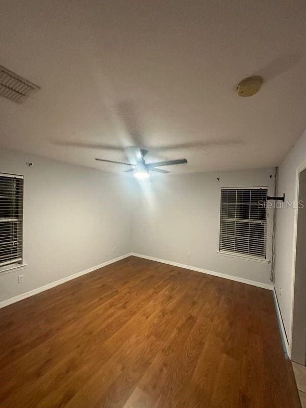 empty room with dark hardwood / wood-style floors and ceiling fan