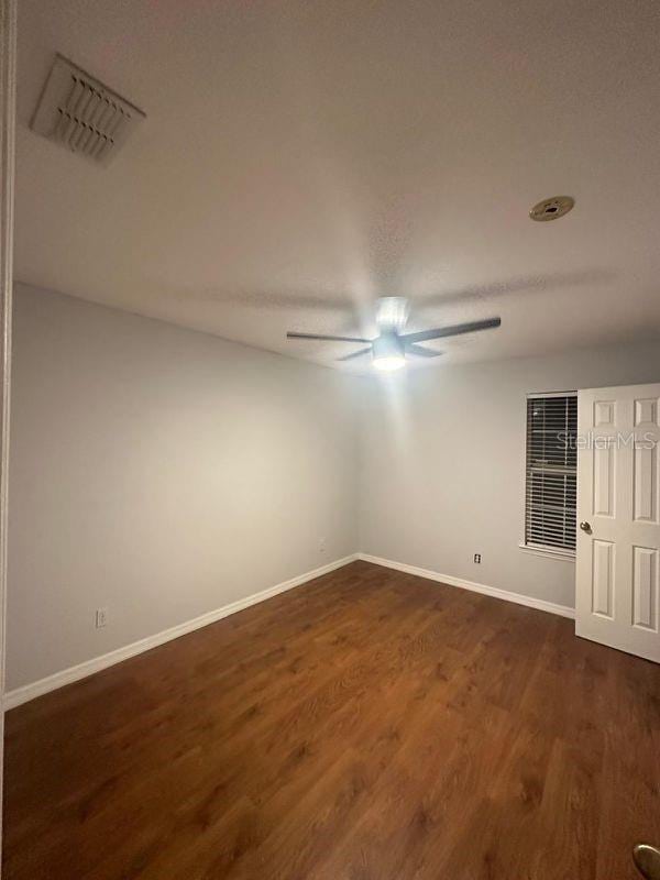 empty room with ceiling fan and dark wood-type flooring