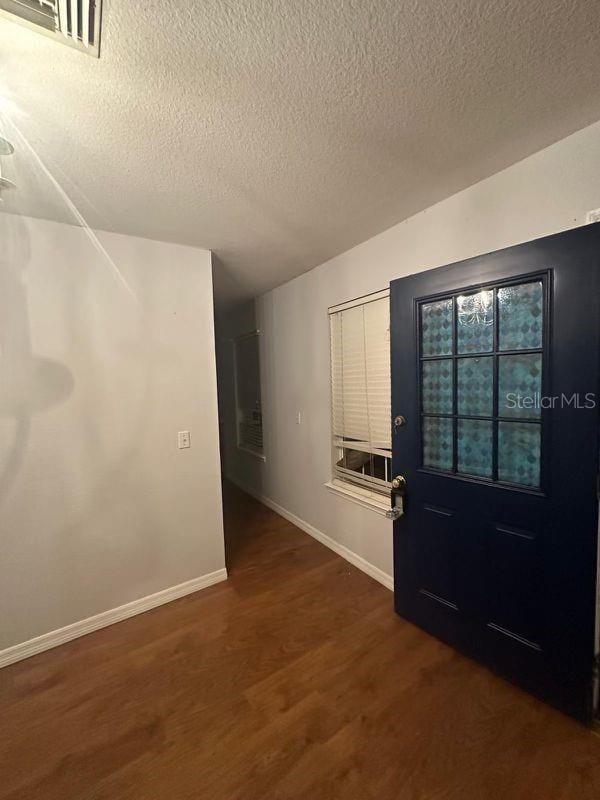 foyer entrance featuring a textured ceiling and dark hardwood / wood-style floors