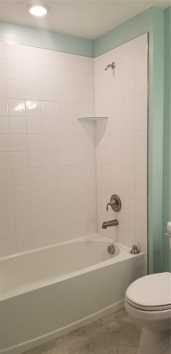 bathroom featuring tiled shower / bath, toilet, and tile patterned floors