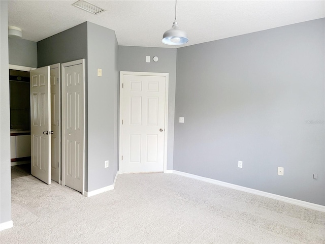 unfurnished bedroom with a textured ceiling and light colored carpet