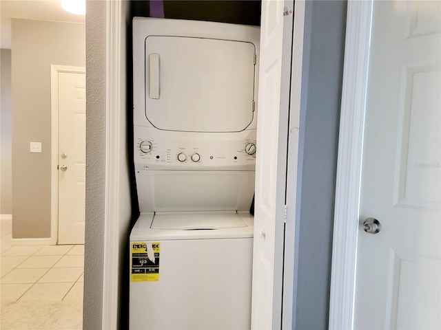 washroom with stacked washer / drying machine and light tile patterned flooring