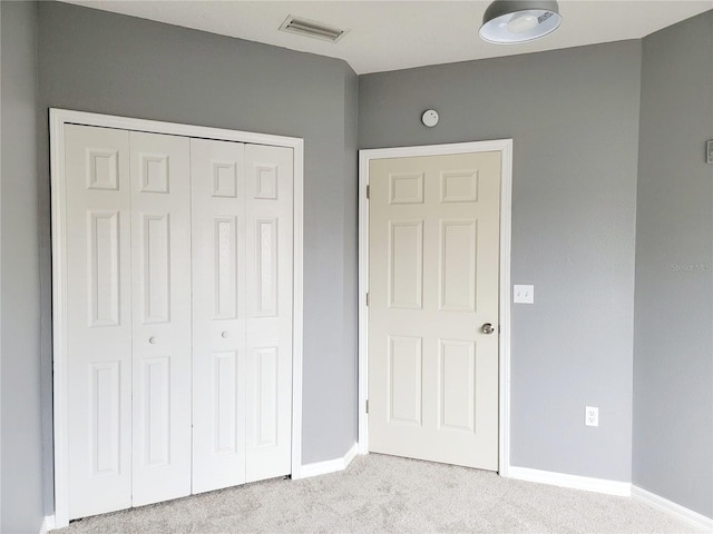 unfurnished bedroom with light carpet and a closet