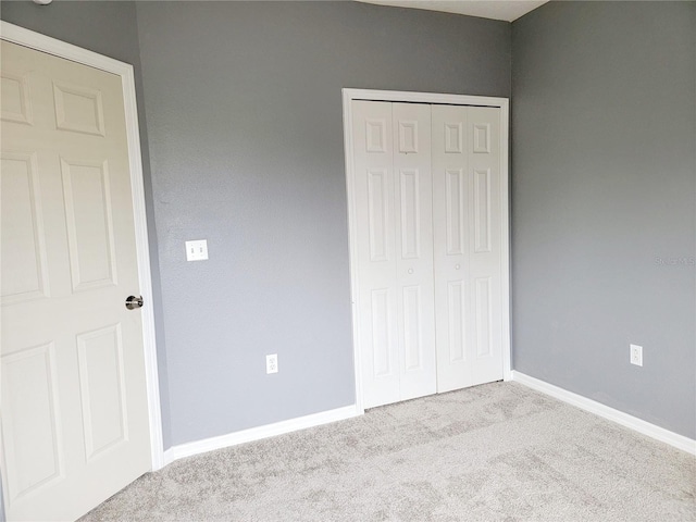 unfurnished bedroom featuring a closet and light colored carpet