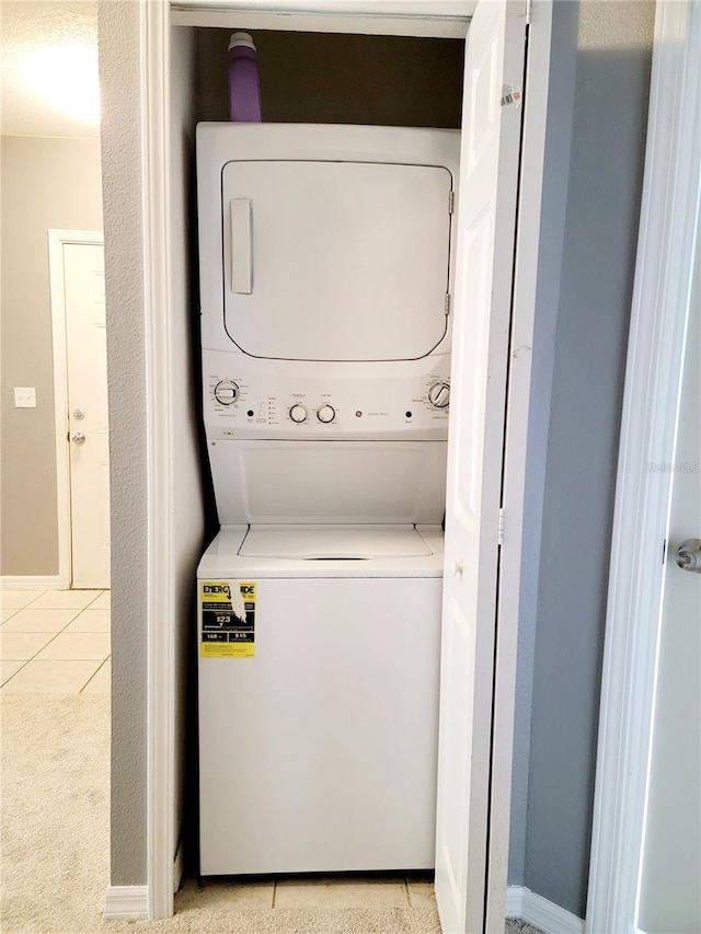 clothes washing area with stacked washer and clothes dryer and light tile patterned floors