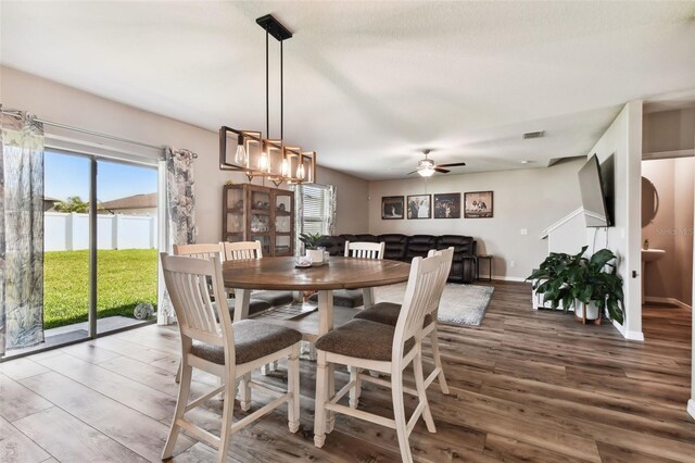 dining area featuring ceiling fan with notable chandelier and dark wood-type flooring