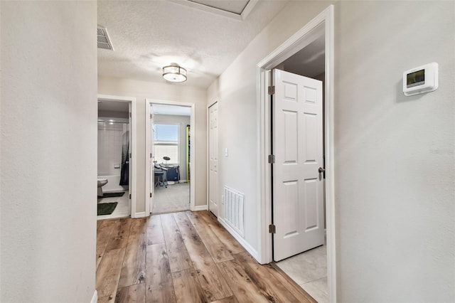 hall featuring a textured ceiling and light wood-type flooring