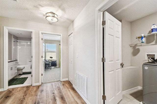 corridor featuring light carpet and a textured ceiling