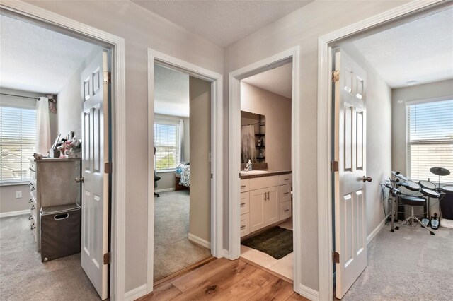 hallway with light colored carpet and sink