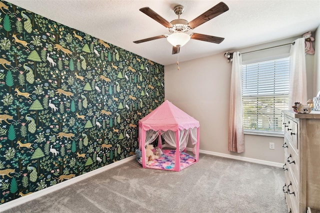 rec room with a textured ceiling, carpet flooring, and ceiling fan