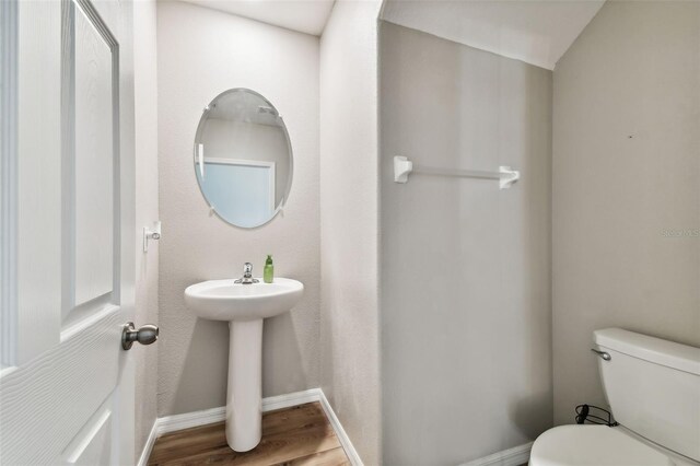 bathroom with toilet, sink, and hardwood / wood-style floors