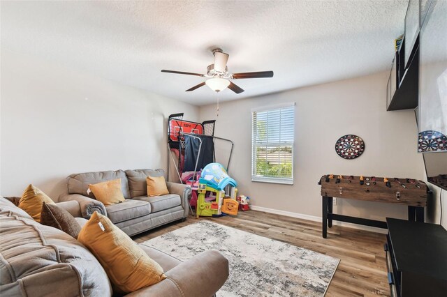 living room with a textured ceiling, ceiling fan, and light hardwood / wood-style floors