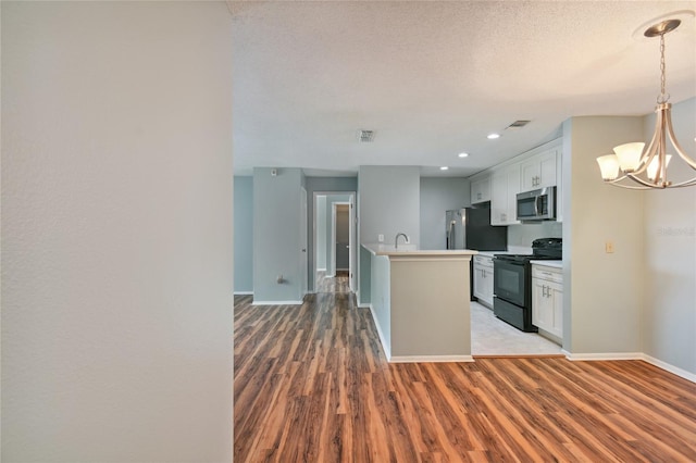 kitchen featuring light wood finished floors, appliances with stainless steel finishes, baseboards, and an inviting chandelier