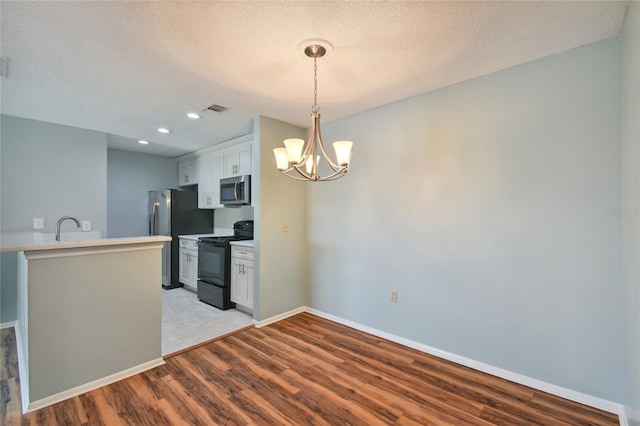 kitchen with visible vents, baseboards, appliances with stainless steel finishes, light wood-style floors, and a chandelier