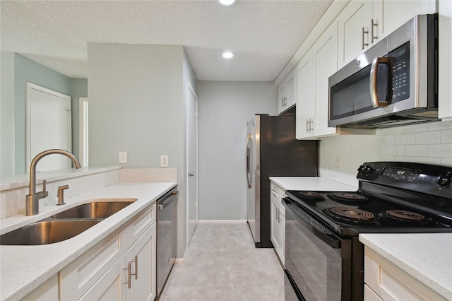 kitchen with tasteful backsplash, stainless steel appliances, a textured ceiling, white cabinetry, and a sink