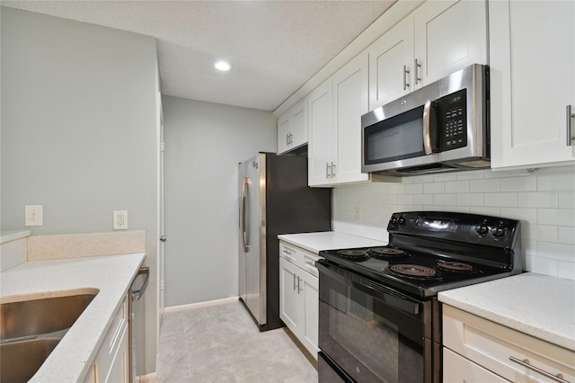 kitchen with a textured ceiling, stainless steel appliances, a sink, white cabinetry, and backsplash