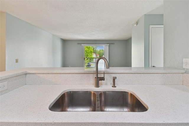 details with a textured ceiling, light stone counters, and a sink