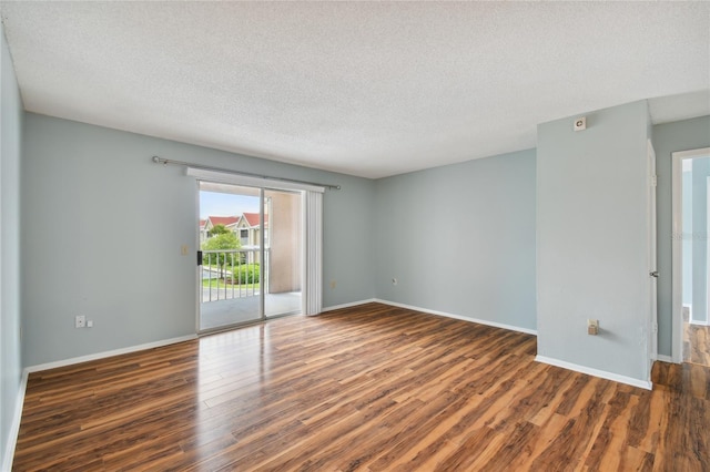 spare room featuring a textured ceiling, wood finished floors, and baseboards