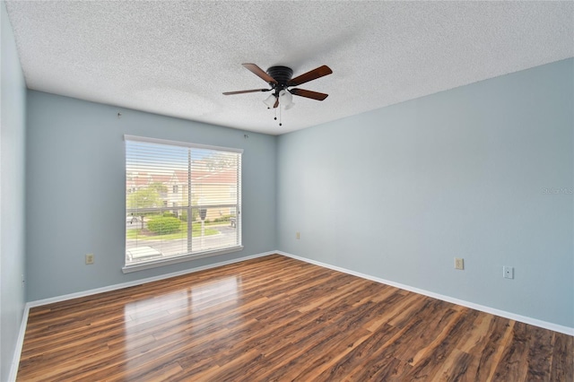 empty room with a textured ceiling, wood finished floors, a ceiling fan, and baseboards