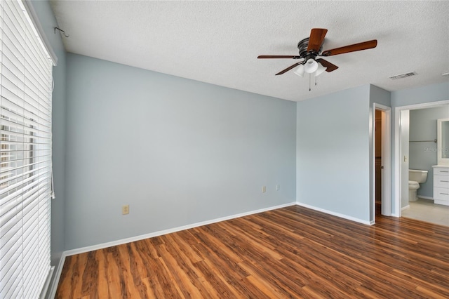 unfurnished bedroom featuring baseboards, a textured ceiling, visible vents, and wood finished floors