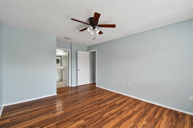 unfurnished bedroom with baseboards, visible vents, stacked washer and clothes dryer, wood finished floors, and a textured ceiling