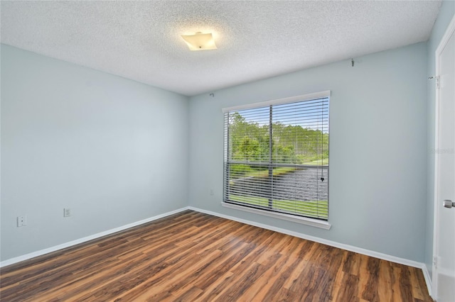 spare room with a textured ceiling, baseboards, and wood finished floors