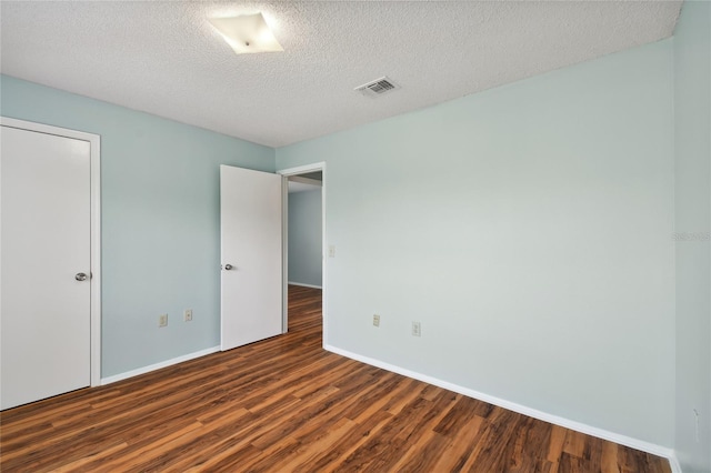 unfurnished room with visible vents, a textured ceiling, baseboards, and wood finished floors