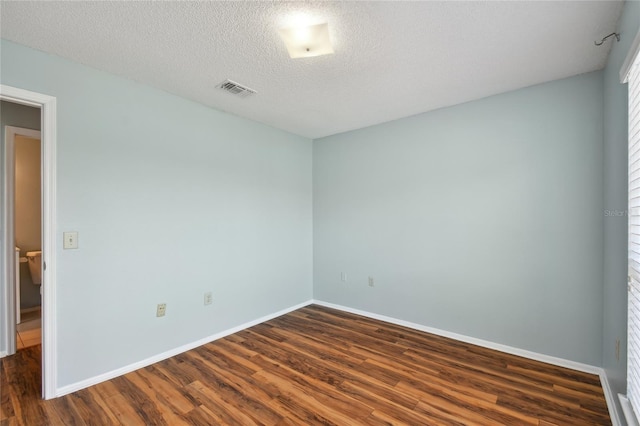 spare room featuring a textured ceiling, baseboards, and dark wood-type flooring