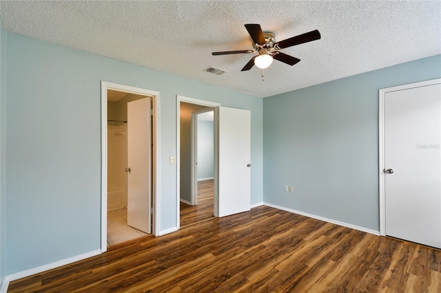 unfurnished bedroom featuring visible vents, a textured ceiling, baseboards, and wood finished floors