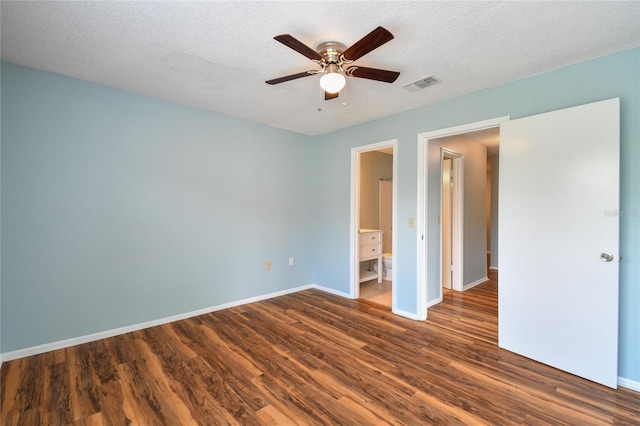 unfurnished bedroom featuring dark wood-type flooring, visible vents, a textured ceiling, and baseboards