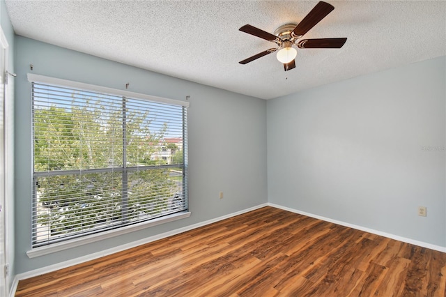 spare room featuring a textured ceiling, ceiling fan, wood finished floors, and baseboards