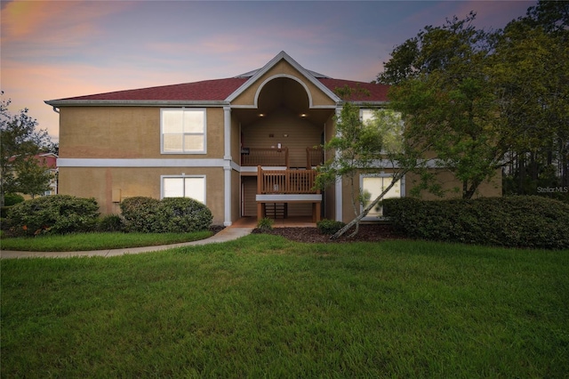 back of property at dusk featuring a yard and stucco siding