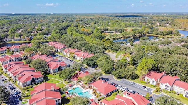 drone / aerial view with a residential view, a water view, and a wooded view