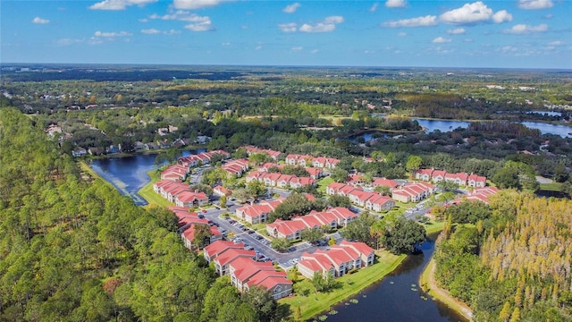 birds eye view of property featuring a water view and a wooded view