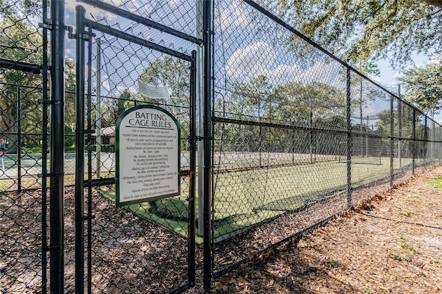 view of tennis court featuring fence and a gate