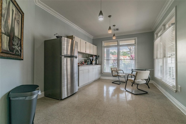 kitchen featuring baseboards, white cabinets, ornamental molding, freestanding refrigerator, and light floors