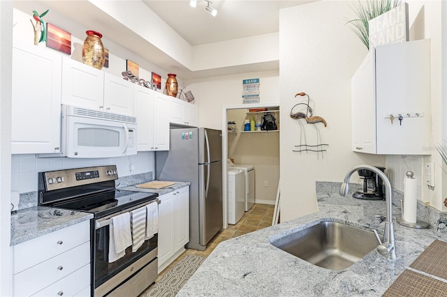 kitchen with backsplash, washing machine and clothes dryer, stainless steel appliances, sink, and white cabinets