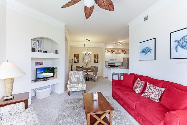 living room with built in shelves, carpet, ornamental molding, and ceiling fan with notable chandelier