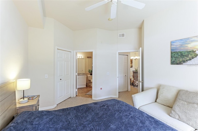 bedroom with ensuite bath, light colored carpet, and ceiling fan