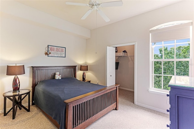 bedroom featuring a spacious closet, ceiling fan, light colored carpet, and a closet