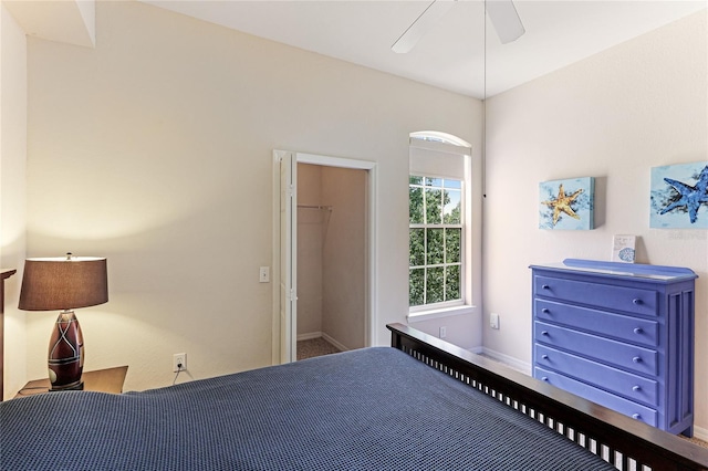 bedroom featuring a walk in closet, ceiling fan, and baseboards