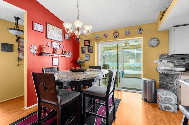 dining space with a textured ceiling, a notable chandelier, and light wood-type flooring