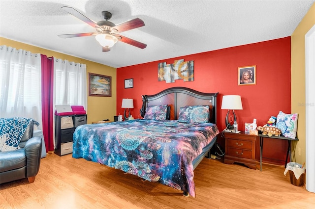 bedroom featuring ceiling fan, a textured ceiling, and light hardwood / wood-style flooring