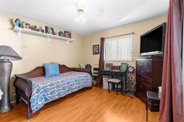 bedroom with a textured ceiling, ceiling fan, and light hardwood / wood-style floors