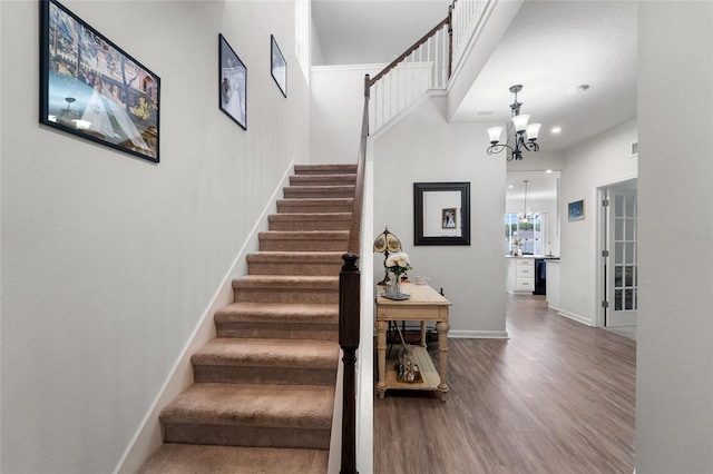 staircase with wood finished floors, an inviting chandelier, baseboards, and recessed lighting