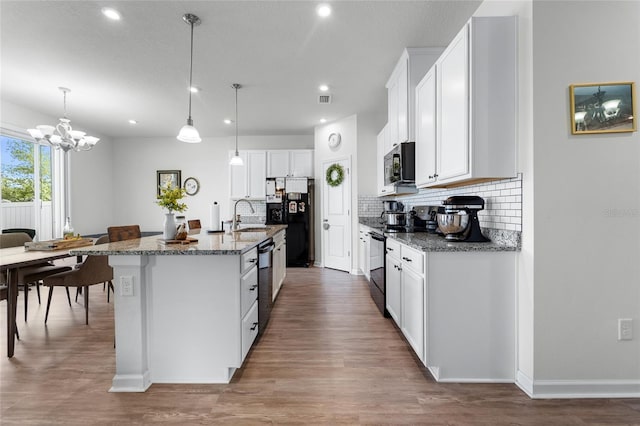 kitchen featuring black appliances, recessed lighting, wood finished floors, a sink, and backsplash